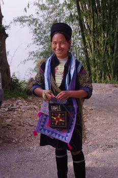 Black Hmong young women in the region of SAPA (North Vietnam). Hmong women still wear a dress. The Black Hmong women are dressed all in black. Dress, jacket and turban are black. It carries the traditional silver jewelry, earrings and necklace.