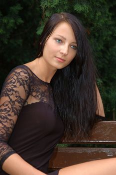 Pretty female model, wearing black skirt. Polish girl sitting at the bank in park.