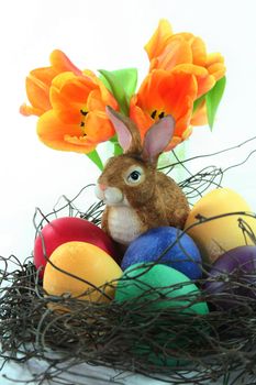 Easter basket with Easter eggs and Easter bunny and tulips on a white background