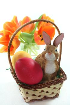 Easter basket with Easter eggs and Easter bunny and tulips on a white background