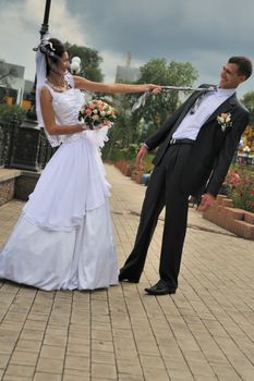 The bride pulls the groom for a tie. Pair young men in wedding day