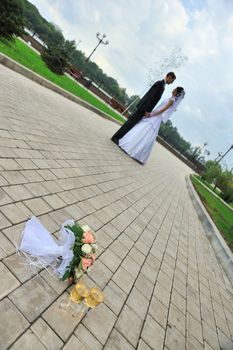 Newly-married couple with wine glass,  bouquet foreground. Pair young men in wedding day