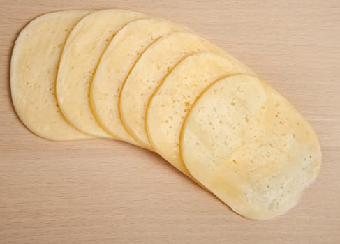 Cutting of cheese on a board on cutting of products. Studio shooting.