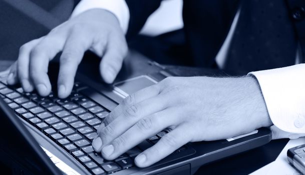 Hands of the businessman above the keyboard laptop. Blue color