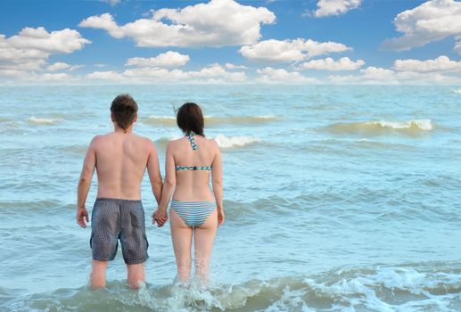 Pair on seacoast. The enamoured guy and the girl walking on coast