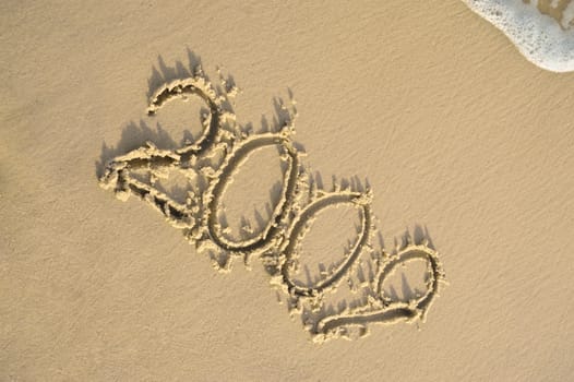 Inscription "2009" on sand. Sea coast with a rolling wave on an inscription