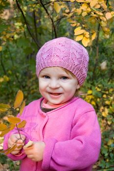 Smiling baby girl with yellow leavesin park