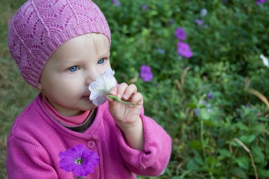 Little girl sniffing flowers in the forest