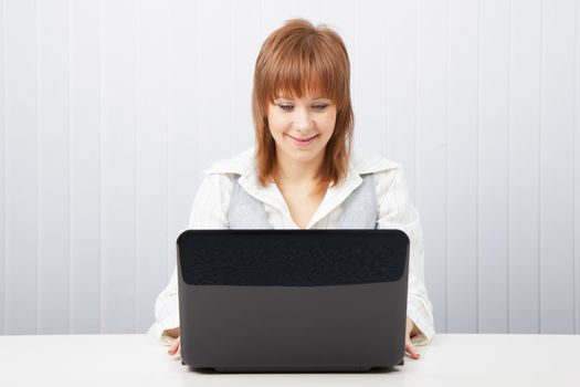 Attractive smiling happy girl with a laptop in the office
