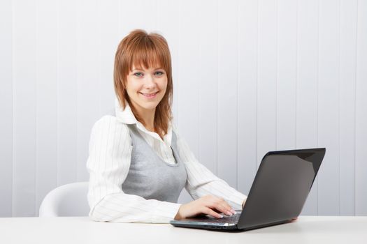 Attractive smiling happy girl with a laptop in the office

