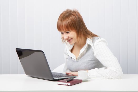 girl in office pleasantly surprised, looking at laptop
