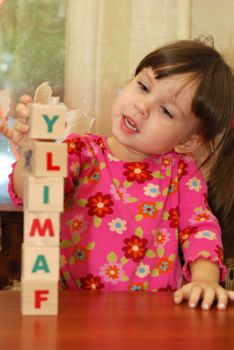 The girl and toy cubes. The child collecting a word family from cubes.