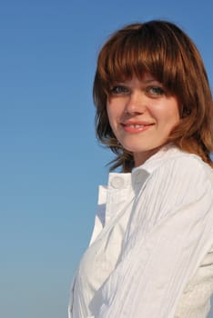 The woman on a background of the sky. The adult girl in white clothes