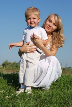 The mother and son. Happy people on a meadow with the clear blue sky