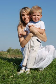 The mother and son. Happy people on a meadow with the clear blue sky