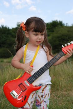 The girl with a guitar. The three-year child with a musical instrument