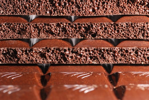 Chocolate. The broken tile of porous black chocolate