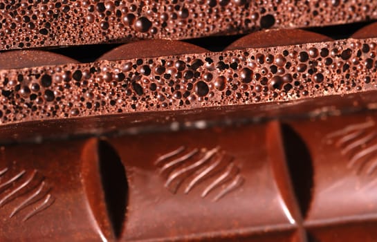 Chocolate. The broken tile of porous black chocolate