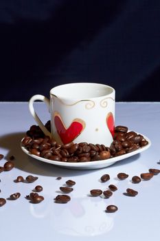 Cup with coffee beans is on the white table.