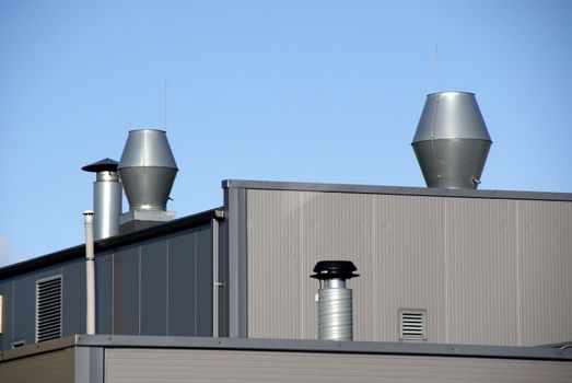 Pipes of ventilation are located on a roof of a  building