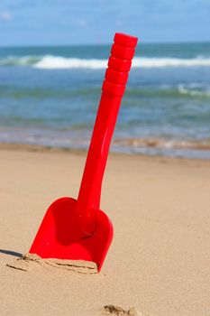 a red shovel at the beach on a sunny day