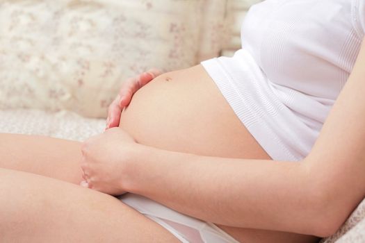 pretty expectant mother in white underwear is stroking belly