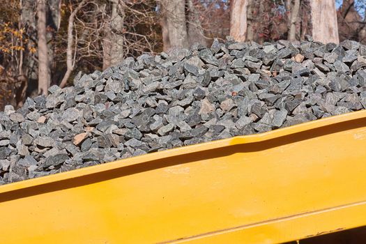 A pile of rocks in a yellow wagon to be used in a construction project
