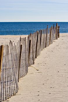An old wooden fence on the beach leading to the ocean