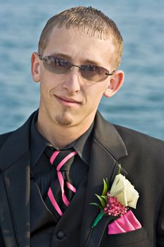 Portrait of a teenage boy in a tuxedo. Background is a blue ocean. The teen is dressed for a high school prom but the photo could be used to represent any formal occasion.