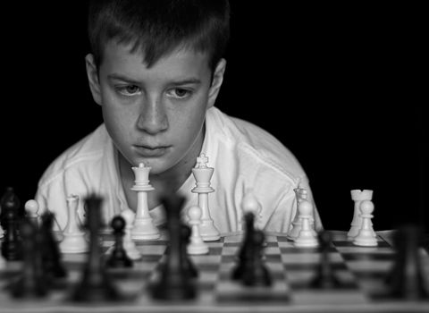 Boy playing chess on black background