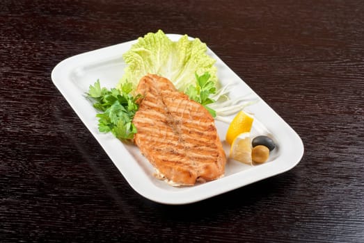 Grilled salmon steak with greens,onion, lemon, lime and olive