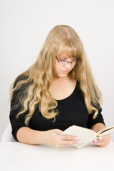 girl with long hair sitting at the table reading
