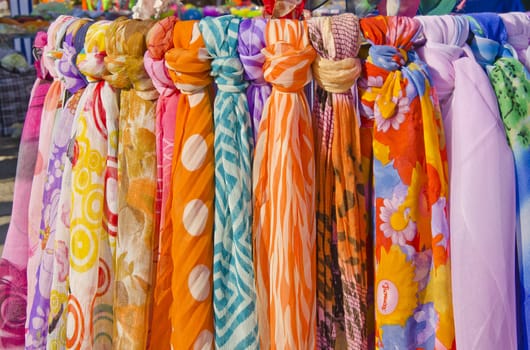 Multicolor shawls and scarves tied on sticks. Summer street fair.
