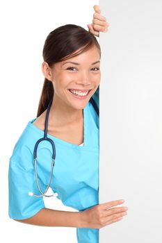 Nurse showing sign billboard blank with copy space. Woman medical professional in scrubs wearing stethoscope smiling friendly isolated on white background.