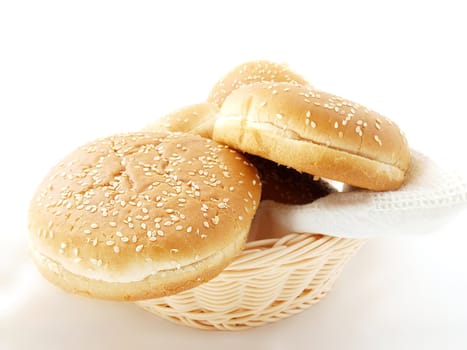 Hamburger buns in wooden basket, with a white towle towards white