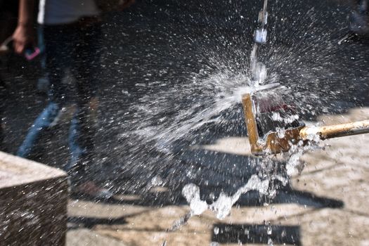 Water pouring a dipper with splashes shining on a bright sunlight