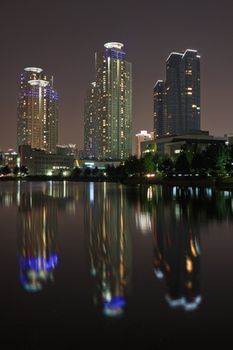 Illuminated apartments reflecting in a pond in night