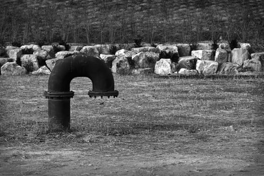 Big black curved metal pipe on gray grass