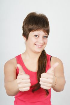 happy girl with thumbs up against a light background. Studio Photos