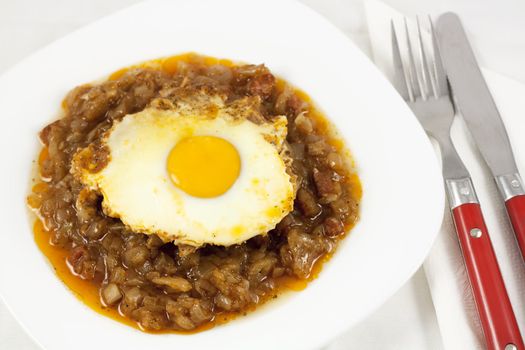 Delicious stew with baked onion, egg and sausages. View from top.