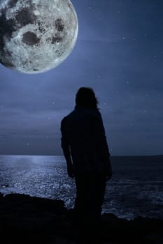 a lone woman looking sadly over the cliffs edge under the full moon in county clare ireland