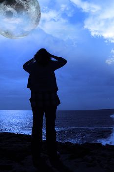 a lone woman looking sadly over the cliffs edge under the full moon in county clare ireland