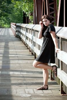 A carefree brunette woman hanging out along an old walking bridge.