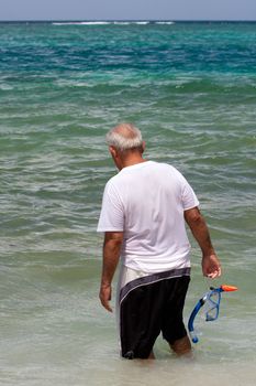 An older elderly man snorkels in tropical waters in the Caribbean off of the Puerto Rican island of Culebra.