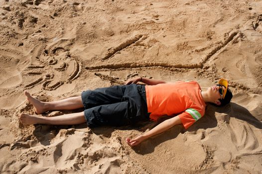 Artistic teenager sunbathing next to his beach cartoon