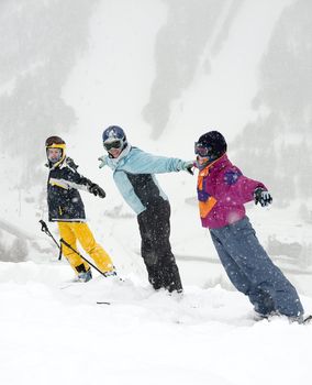Happy skiers standing in the falling snow