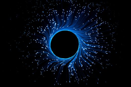 Illuminated blue fiber optic light strands forming a ring against a black background