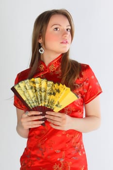 The beautiful young girl in a red Chinese dress with a yellow fan