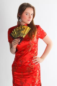 The beautiful young girl in a red Chinese dress with a yellow fan
