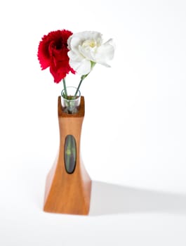 Single red and white spray carnation blossoms in a carved teak vase with unique opening showing the stem